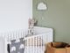 Berceau avec peluche et coussins, lampe nuage sur mur vert, panier en osier