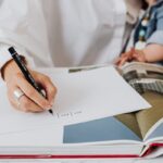 Une main écrit sur du papier, un livre ouvert, une personne tient un enfant